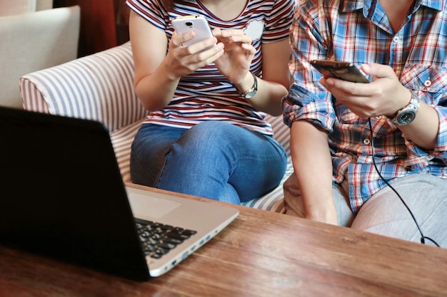 Women touching screen and man typing laptop on wood table