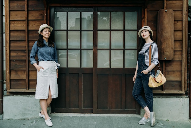 Women tourists standing relying on wall wooden