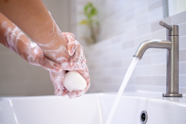 Women wash their hands with soap on the bathroom sinks.