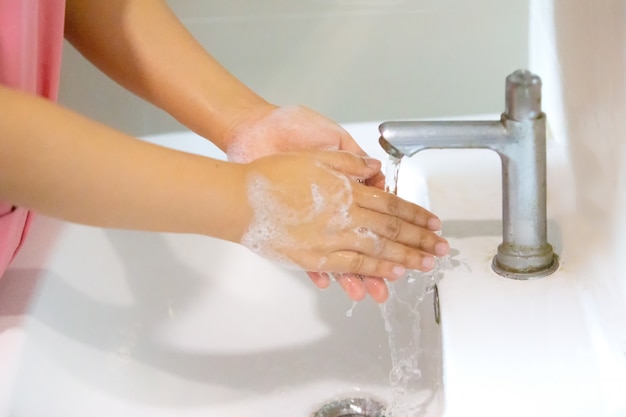 women washing hand with foam soap in bathroom sink. Covid-19 and coronavirus concept