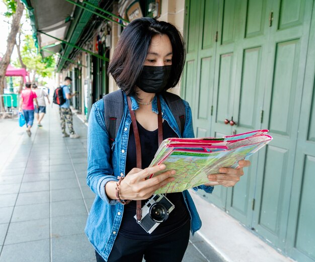 Women wearing health mask look a map for travel at the city