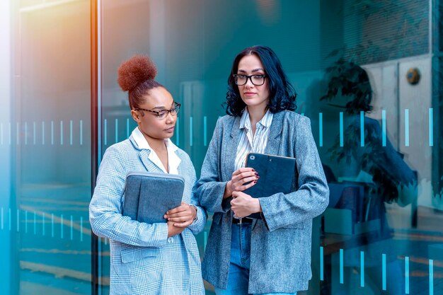 women wearing office suits with digital tablet talking and smiling Joyful business partners concept