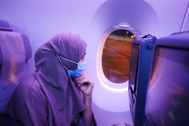 Women with a face mask sitting on airplane seats in the cabin