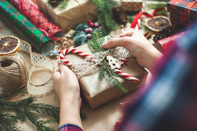 Photo womens hands decorate the box with the christmas gift table with decor and materials for decoration