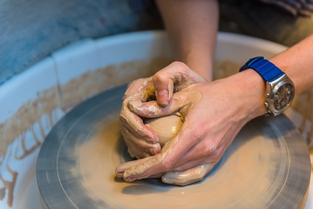 Womens hands of a potter creating an earthen jar