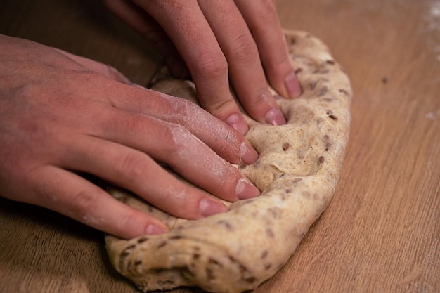 Womens hands roll out dough from whole grain flour making homemade bread