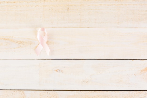 Womens health symbol in pink ribbon on wooden board.