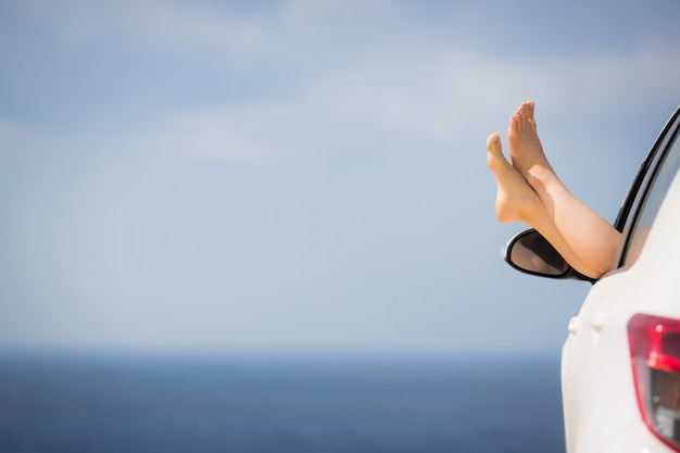 Womens legs against blue sea and sky Summer vacations concept