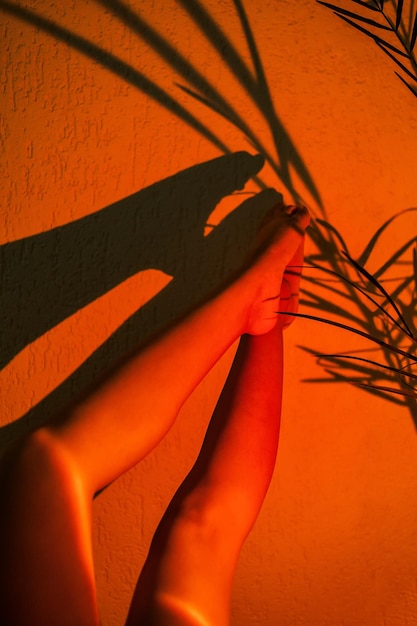 Womens legs pointing upwards in the beam of a lamp projecting the sunset