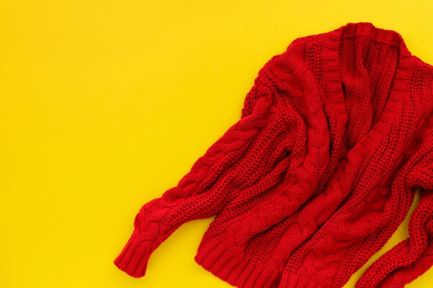 Womens red sweater on yellow background Flat lay top view