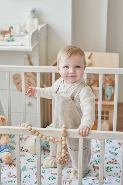 Wonderful baby boy with blue eyes in crib Child playing with toys in nursery Early development kindergarten nursery playroom Children's Day Mother's Day