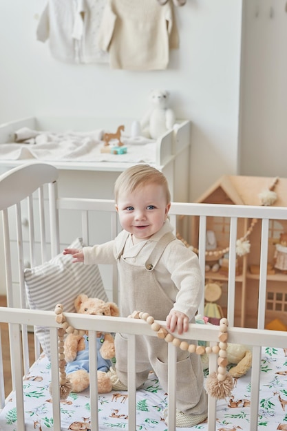 Wonderful baby boy with blue eyes in crib Child playing with toys in nursery Early development kindergarten nursery playroom Children's Day Mother's Day