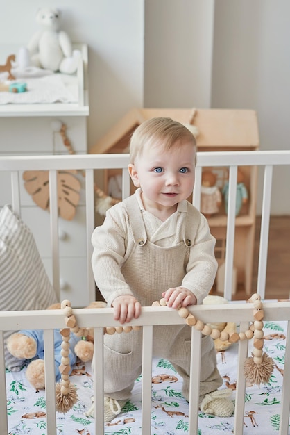 Wonderful baby boy with blue eyes in crib Child playing with toys in nursery Early development kindergarten nursery playroom Children's Day Mother's Day