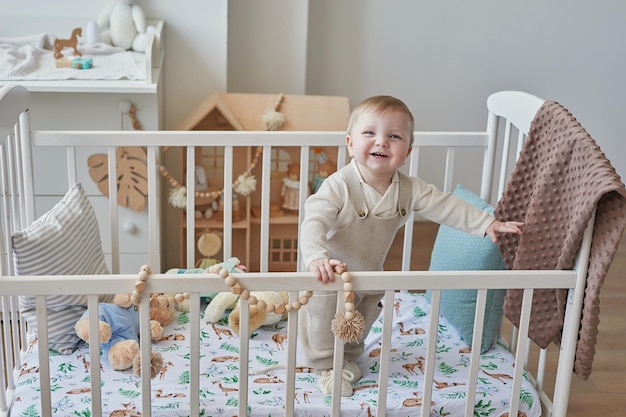 Wonderful baby boy with blue eyes in crib Child playing with toys in nursery Early development kindergarten nursery playroom Children's Day Mother's Day