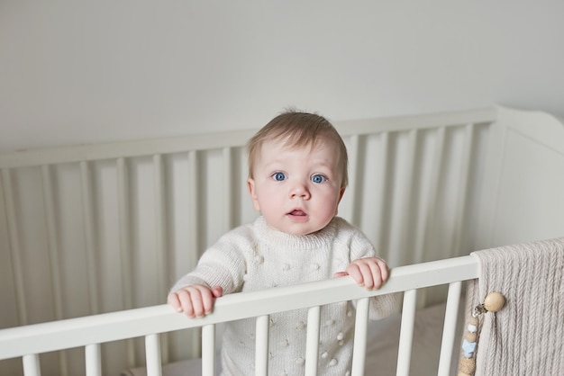 Wonderful baby boy with blue eyes in crib Child playing with toys in nursery Early development kindergarten nursery playroom Children's Day Mother's Day