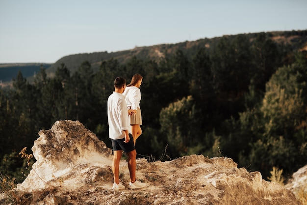 Wonderful couple holding hands are walking along the rocky mountain