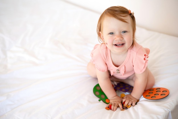 A wonderful cute little baby girl with red hair plays and laughs Birthmark Hemangioma White background space for text Lifestyle