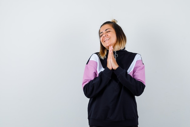 Wonderful lady in sweatshirt keeping hand in praying gesture and looking peaceful