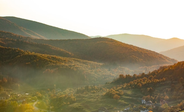 Wonderful scene of sunrise in the mountains landscape with sunny beams The village is located in the valley and is covered with a light morning fog