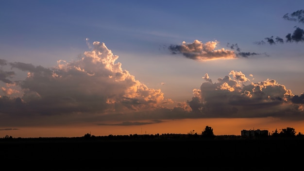 Wonderful view of cumulus clouds sky with the orange sun light at sunset of summer. Beautiful cloudscape as nature background panorama at sundown. Weather of natural daylight golden sunshine