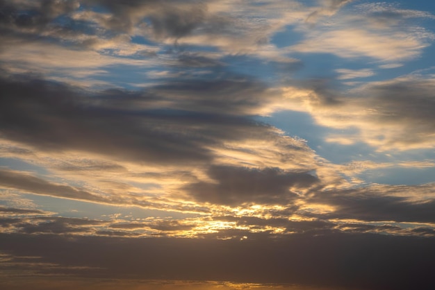 Wonderful view of cumulus clouds sky with the orange sun light at sunset of summer. Beautiful cloudscape as nature background panorama at sundown. Weather of natural daylight golden sunshine