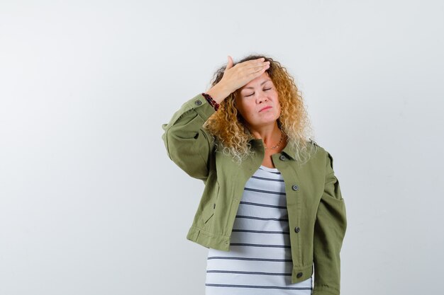 Wonderful woman in green jacket, shirt suffering from headache and looking painful , front view.