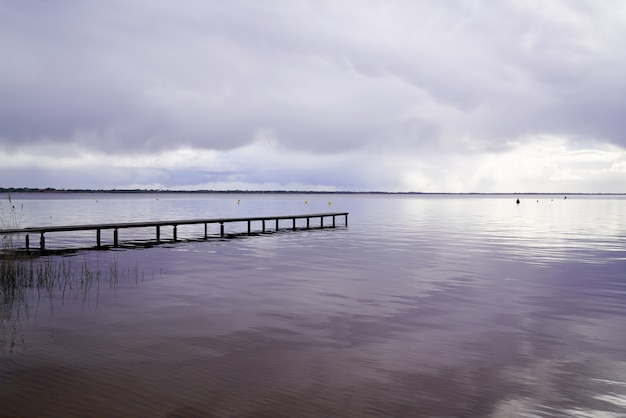 Wood access empty pontoon sunrise blue water winter on Lake Hourtin in Gironde france