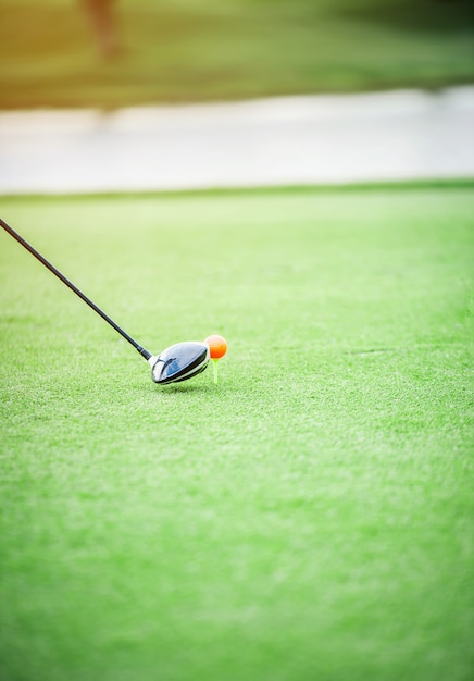 Wood golf club head is about to hit a golf ball on the green grass