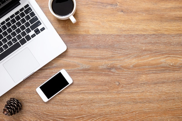 Wood office desk table with smartphone, laptop and cup of coffee.