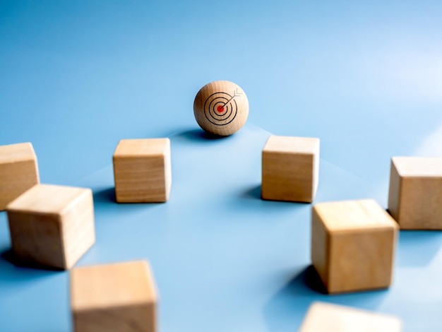 Wood sphere leader with target icon in front of the wooden cube blocks on blue background Concept of leadership business target and success motivation and definite chief aim