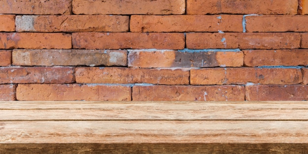 Wood table top in front of brick background and copy space. display or montage products