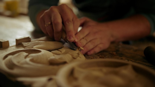 Wood worker hands carving wood in slow motion in carpentry workshop Unrecognized carpenter decorating product in studio Closeup unknown handyman making ornament on wood indoors