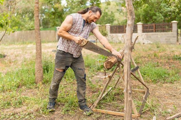 A woodcutter sawing wood in an orchard