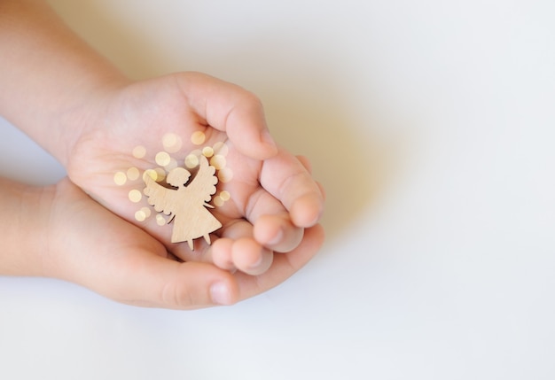 Wooden angel in children's hands on a white background, celebration, dream, Hope - Concept