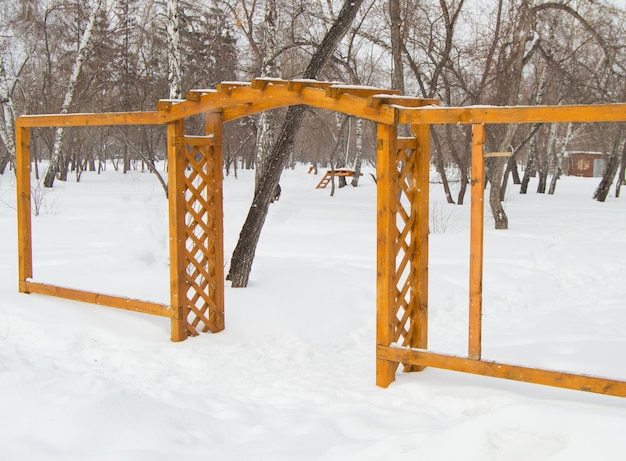 Wooden arch with grating in the Park in winter cloudy day and snow