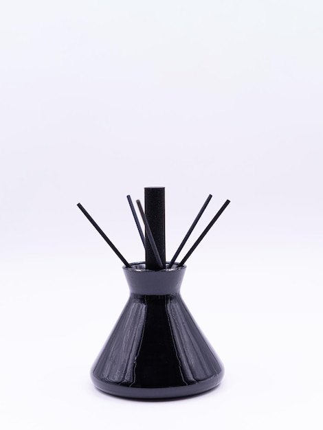 Wooden aroma sticks in a glass flask filled with flavor liquid substance isolated over white background side view