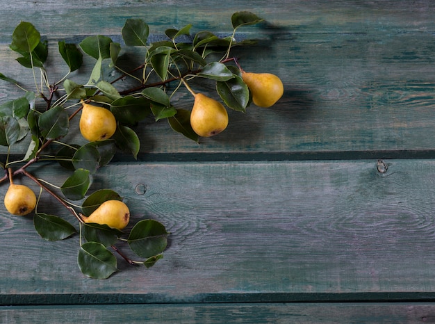 Photo on a wooden background a branch of a pear and five ripe yellow pears