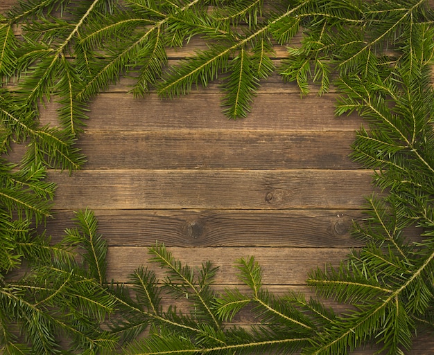 Wooden background with fir branches on the edge.