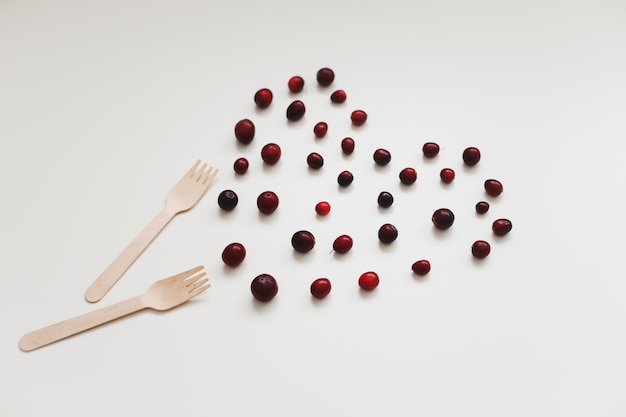 Wooden bamboo cutlery and berries on white background zero waste no plastic ecofriendly concept