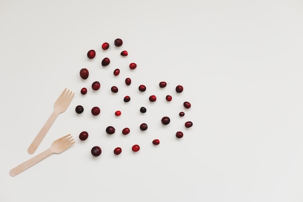 Wooden bamboo cutlery and berries on white background zero waste no plastic ecofriendly concept