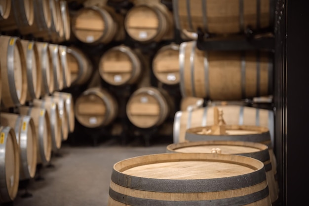 Wooden barrel with copy space on top and winery vault interior on background, soft focus