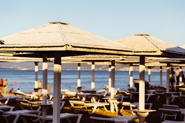 Wooden beach umbrellas on a blurred background of sun loungers and the sea