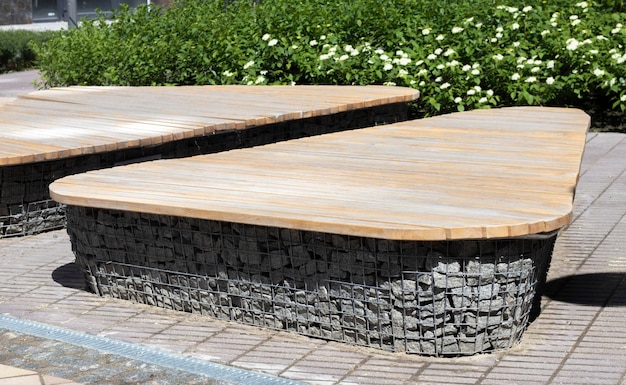 Wooden benches from gabion baskets with stones inside Wood mounted on gabions Benches of modern design There is a recreation area Detail of a low gabion wall with a wooden top