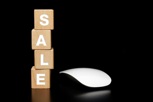 Wooden block with the word SALE and a mouse on a dark background. Business sales and discounts shop