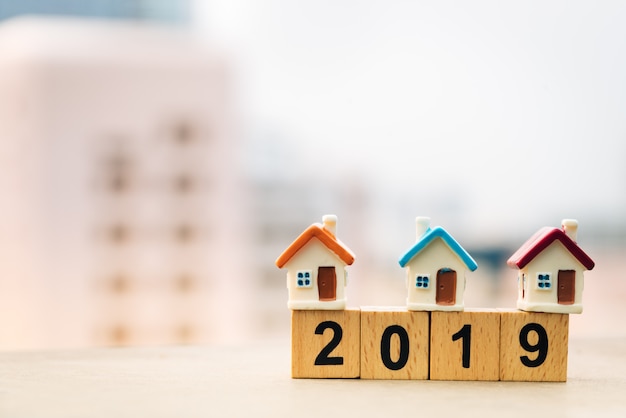 Wooden block word 2019 New year and house on top of coins stack.