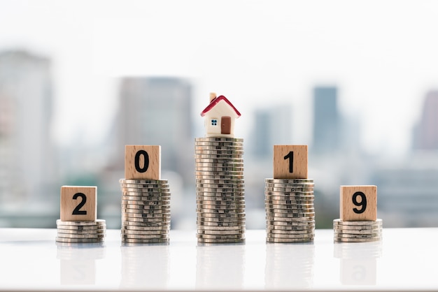 Wooden block word 2019 New year and house on top of coins stack.