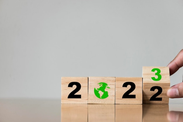 Wooden blocks with 2023 lettering and green globe icon It shows that in 2023 we must pay attention and reduce pollution to help reduce global warming