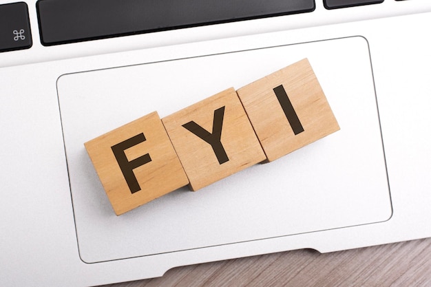 Wooden blocks with letters FYI on keyboard