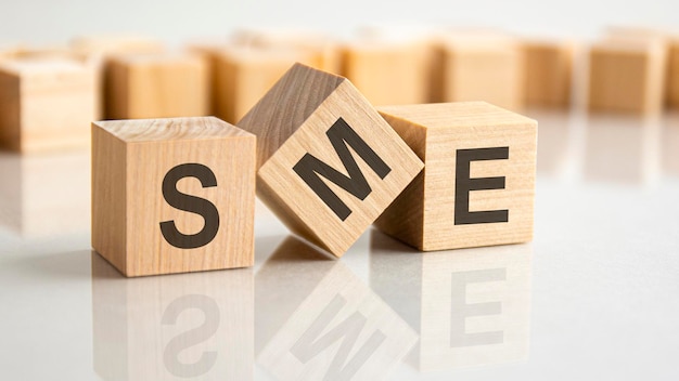 Wooden blocks with letters SME - short for Small Medium Enterprise on a gray table, business concept