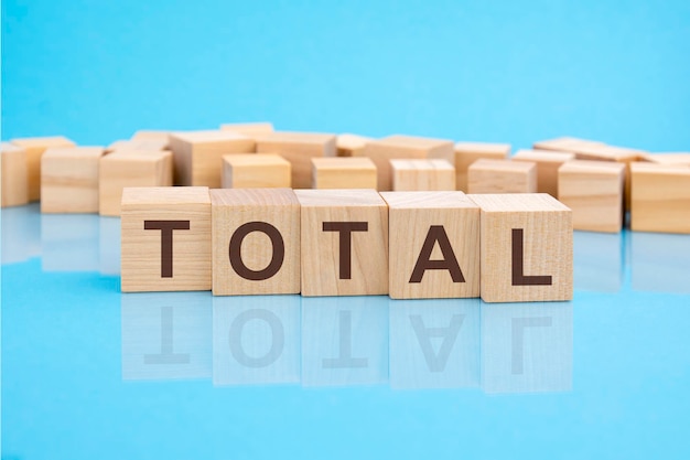 Wooden blocks with the letters Total on the bright surface of a blue table the inscription on the cubes is reflected from the surface business conceptual